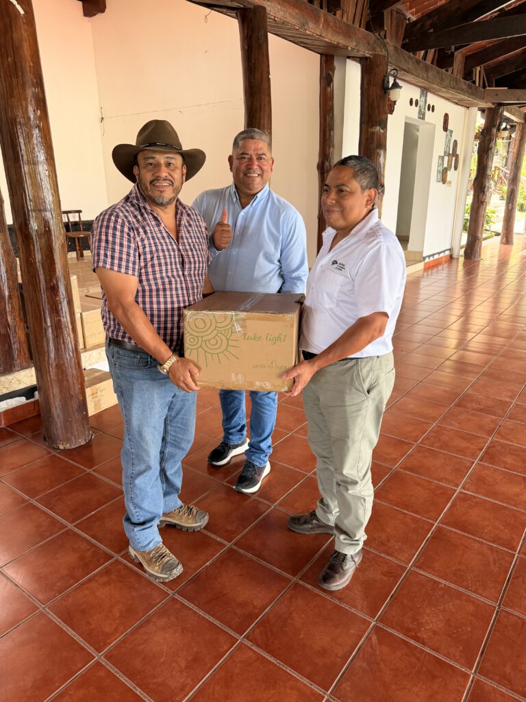Three men holding a box of solar lights