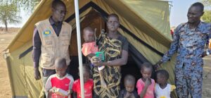 Woman holds child and solar light in refugee tent in Sudan