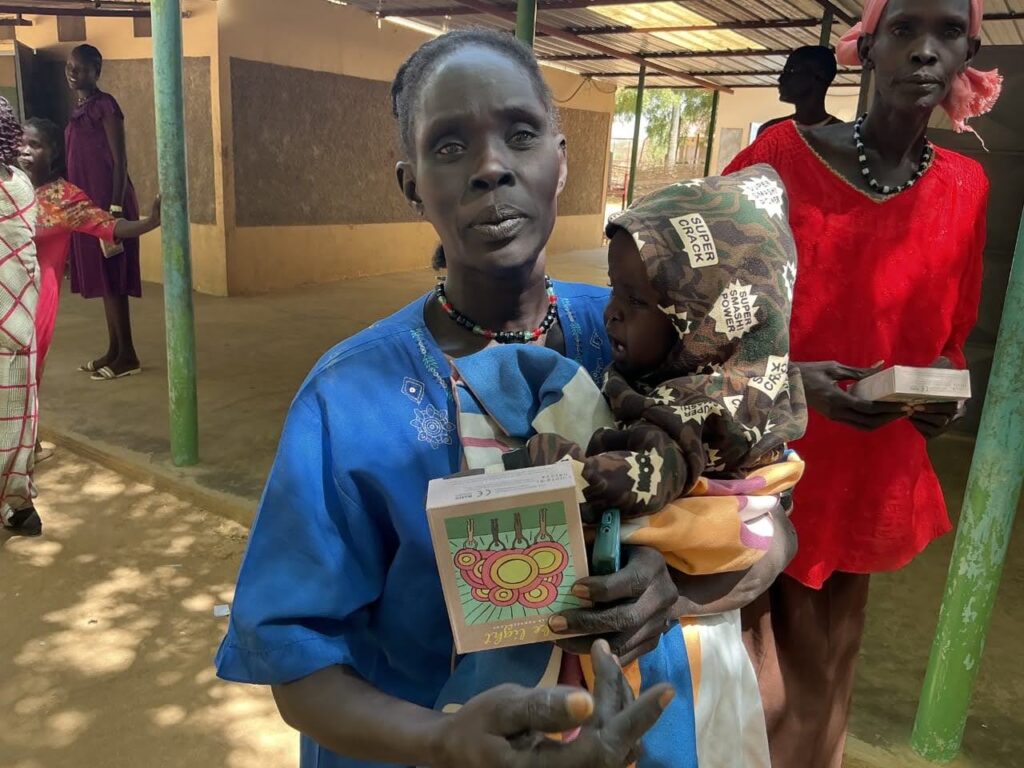Mother in blue shirt holds child and solar Luke Light
